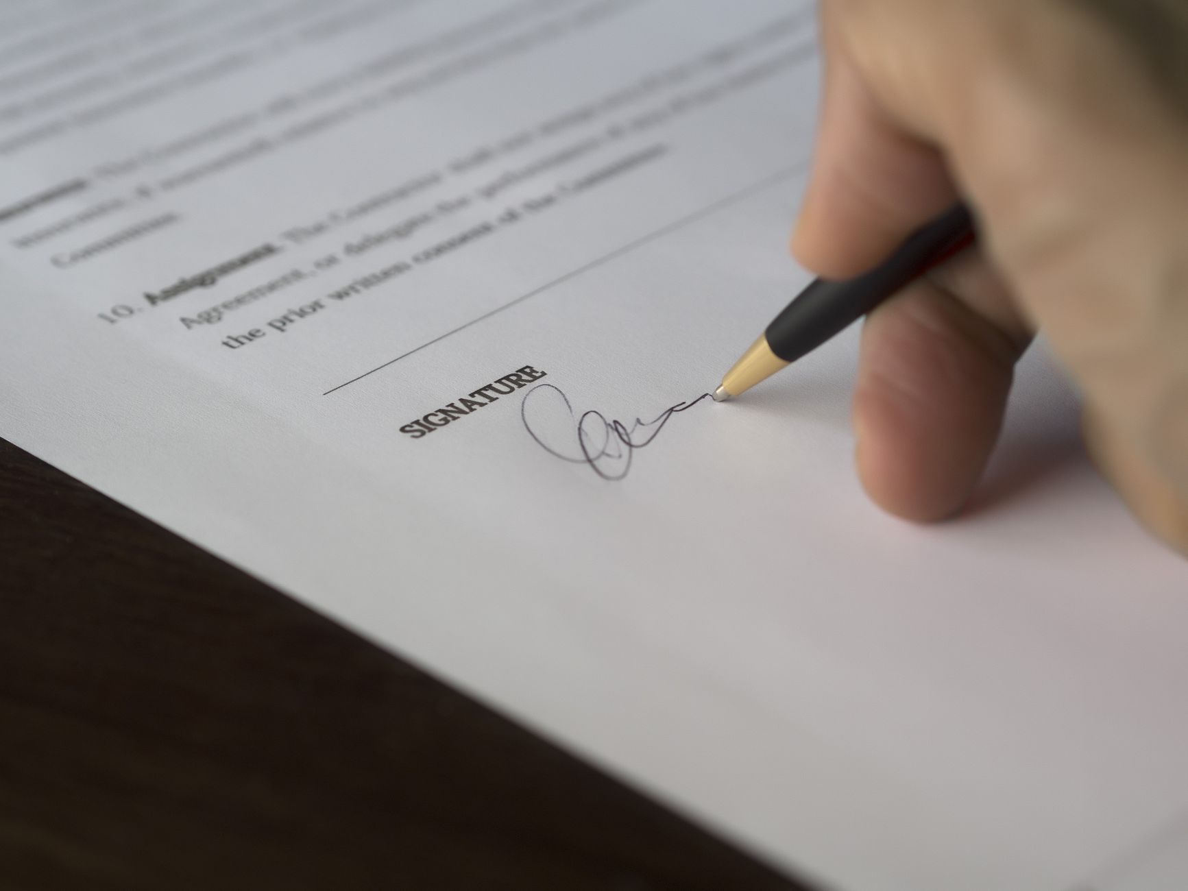 A hand signing a document with a pen